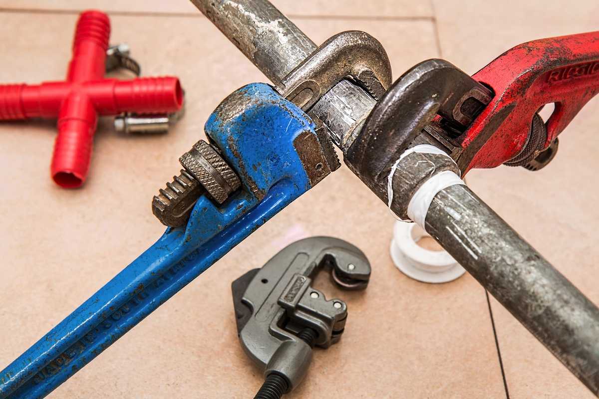 Clés à tuyau, tuyau en cuivre et outils de plomberie disposés sur établi