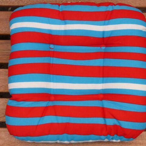 Coussin rayé rouge, bleu et blanc posé sur banc en bois