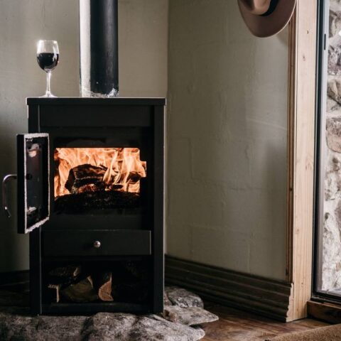 Un poêle à bois en fonctionnement avec un verre de vin posé dessus