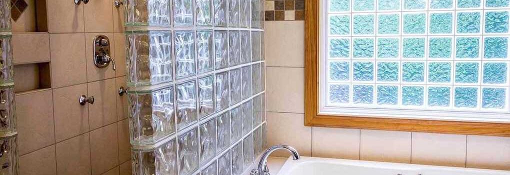 Salle de bain avec baignoire blanche, douche, et fenêtre en carreaux de verre coloré