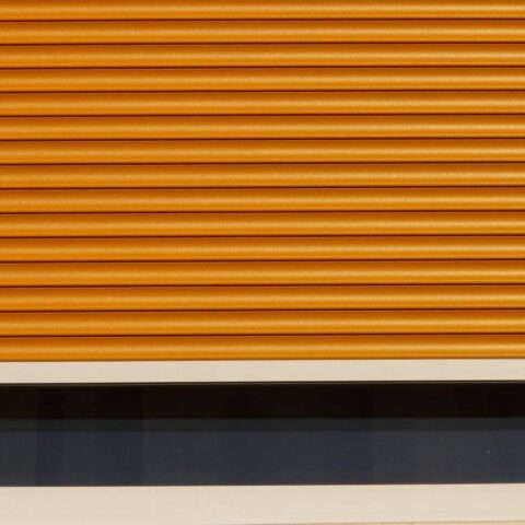 Volet roulant orange partiellement descendu sur une fenêtre