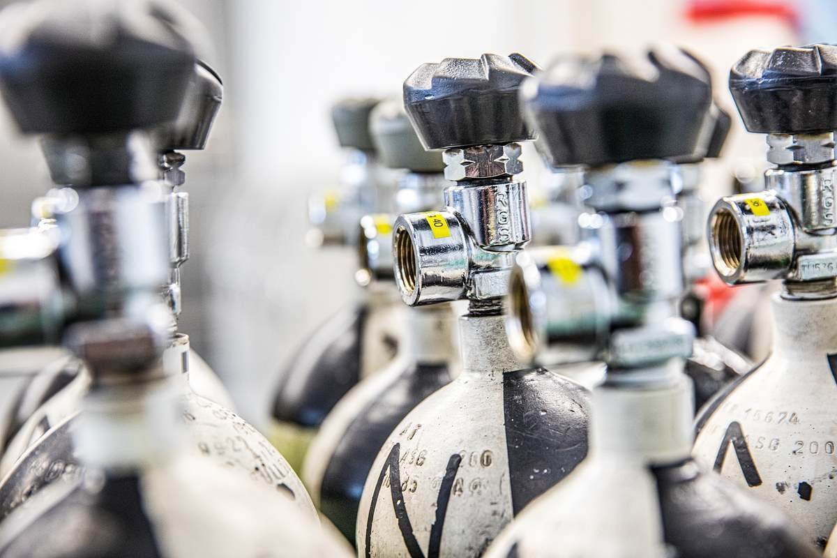 Cylindres de gaz avec valves et étiquettes jaunes alignés en rangée Cylindres de gaz avec valves et étiquettes jaunes alignés en rangée