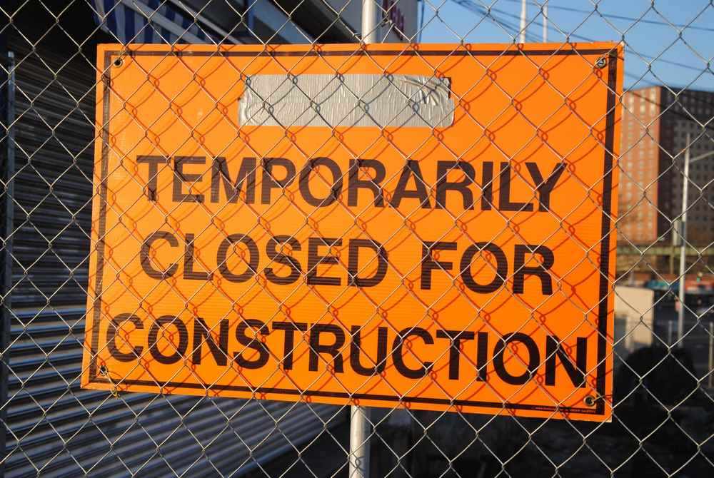 Panneau orange sur clôture indique fermeture temporaire pour travaux