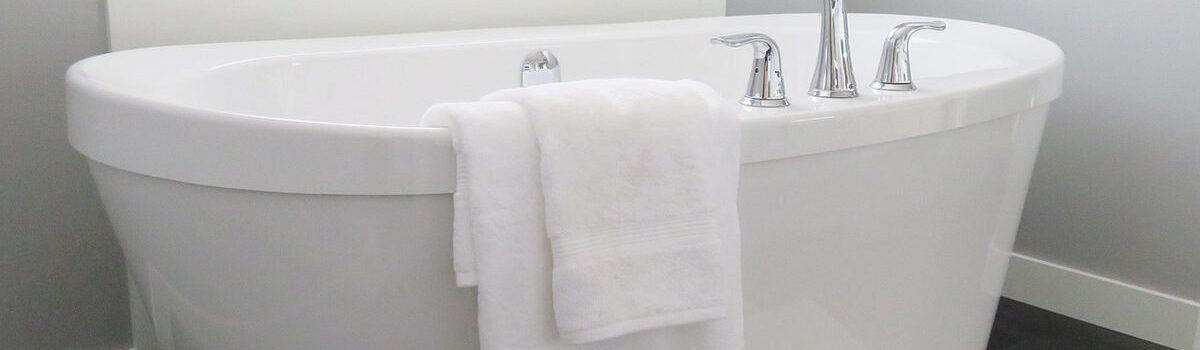 Une baignoire blanche avec robinet, serviettes et tapis dans une salle de bain