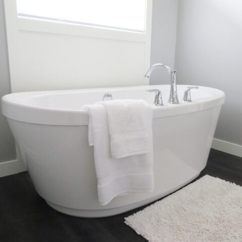 Une baignoire blanche avec robinet, serviettes et tapis dans une salle de bain